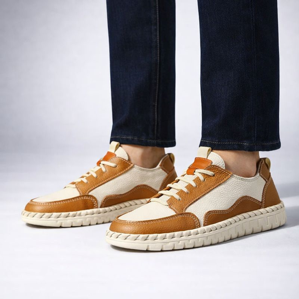 Brown and white sneakers worn with dark jeans on a light gray background