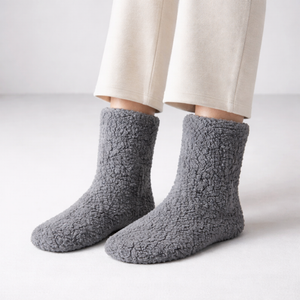 Gray fuzzy socks worn with beige pants on a light gray background