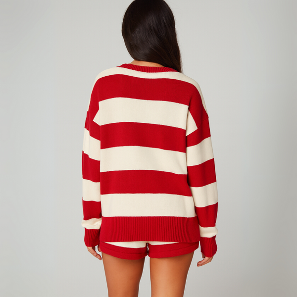 Person wearing a red and white striped sweater and shorts on a plain background