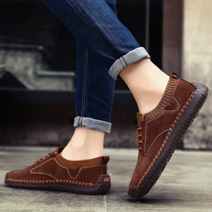 Brown leather shoes worn with rolled-up jeans on a blurred background