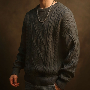 Person wearing a dark gray cable knit sweater against a brown background