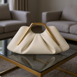 White handbag with gold handle on a glass table in a living room setting