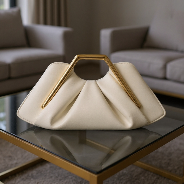 White handbag with gold handle on a glass table in a living room setting