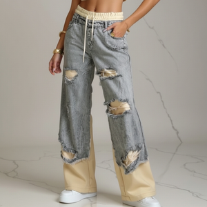 Person wearing ripped jeans with beige accents on a neutral background