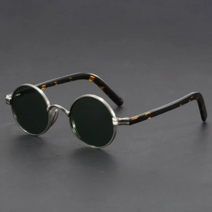 Round sunglasses with metallic frame and tortoiseshell accents on a dark background