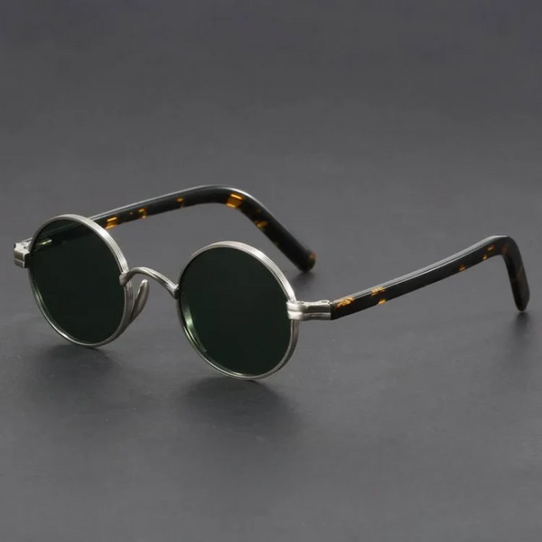 Round sunglasses with metallic frame and tortoiseshell accents on a dark background