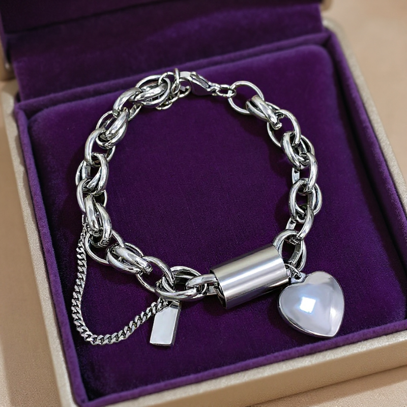 Silver chain bracelet with heart charm on a purple cushion in a box