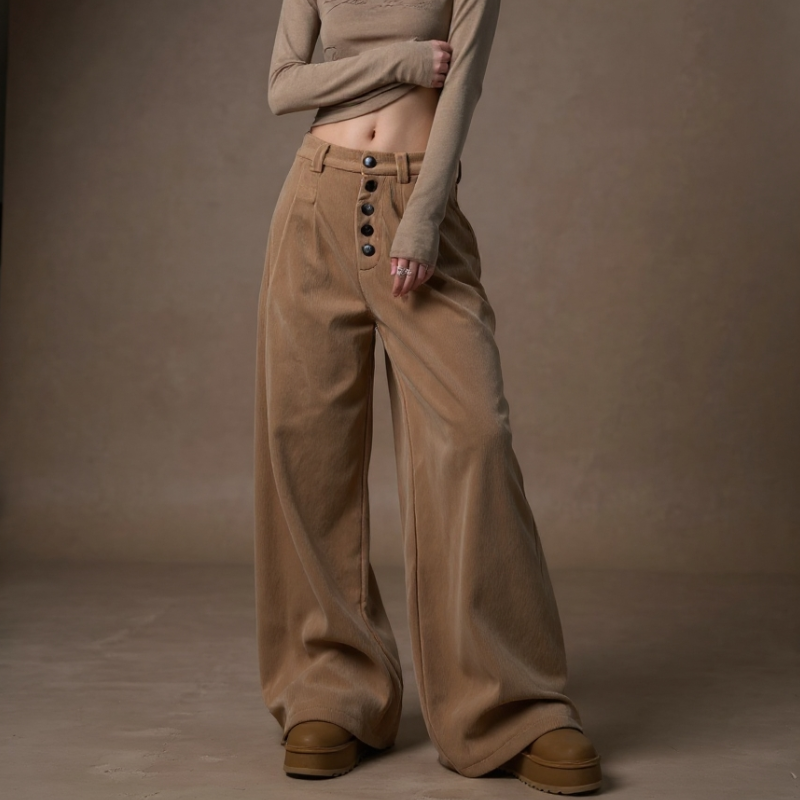 Person wearing a beige outfit with wide-leg pants against a brown background