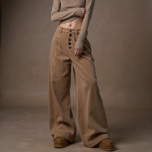 Person wearing a beige outfit with wide-leg pants against a brown background