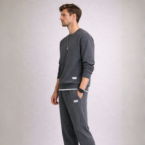 Man wearing a gray sweatshirt and pants on a light gray background