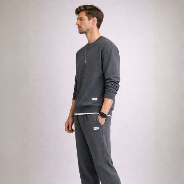 Man wearing a gray sweatshirt and pants on a light gray background