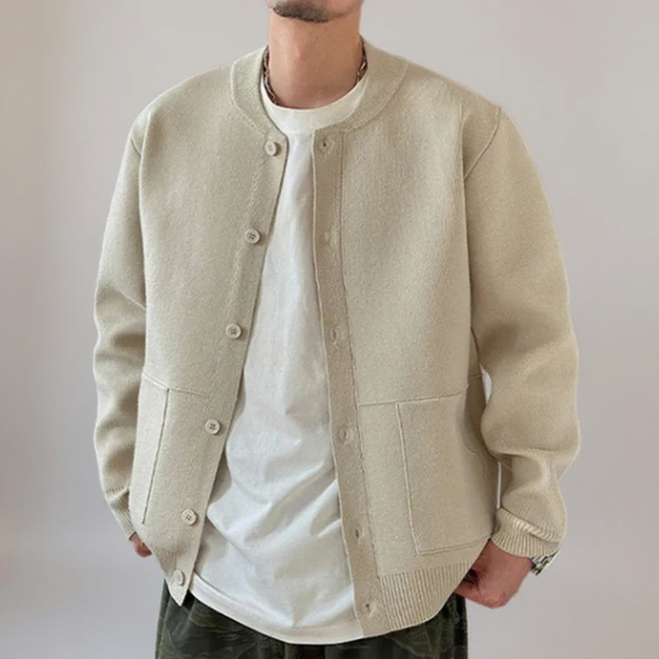 Person wearing a beige cardigan over a white shirt on a plain background