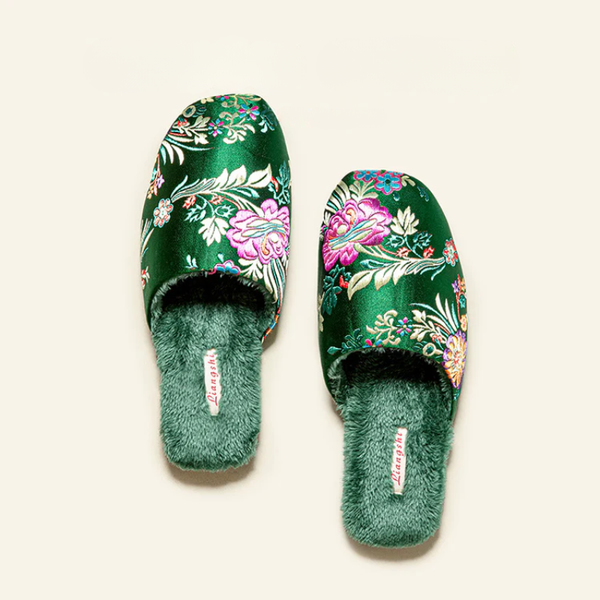 Green floral patterned slippers with fuzzy sole on a light beige background
