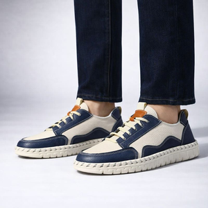 Navy and beige sneakers worn with dark jeans on a light background