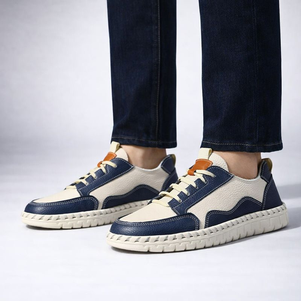Navy and beige sneakers worn with dark jeans on a light background