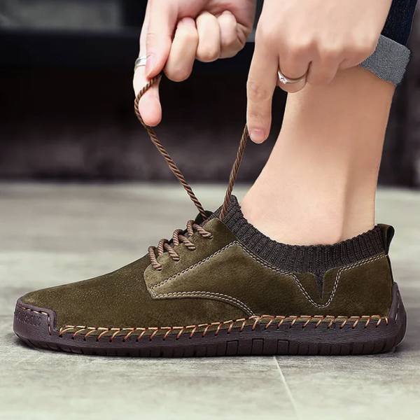 Person tying a brown sneaker on a neutral background