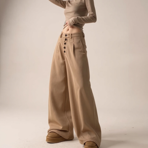 Person wearing beige high-waisted pants with button details on a plain background