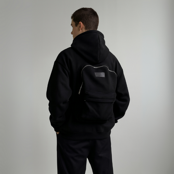 Person wearing a black hoodie with a logo on the back against a plain background