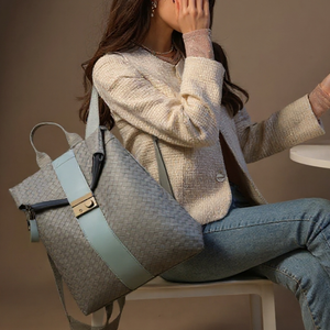Woman sitting with a textured handbag on a neutral background