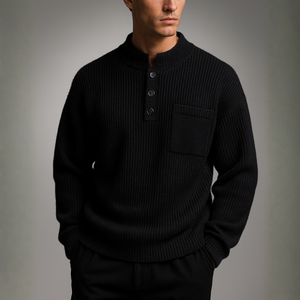 Man wearing a black ribbed sweater against a gray background