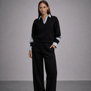 Woman wearing a black outfit with a striped shirt against a gray background