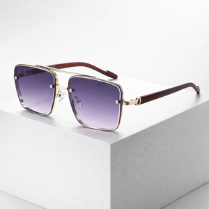 Sunglasses with gold frame and purple gradient lenses on a light gray surface