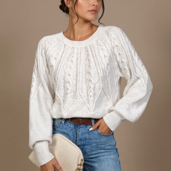 Woman wearing a white cable knit sweater and blue jeans against a beige background