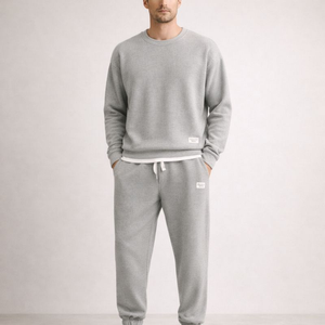 Person wearing a gray tracksuit with a plain background
