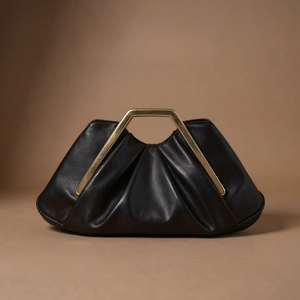 Black handbag with gold handle on a brown background