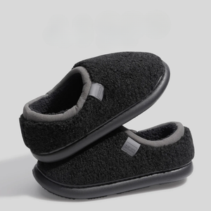 Pair of black slippers with gray soles on a light gray background