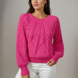 Person wearing a bright pink cable knit sweater against a neutral background