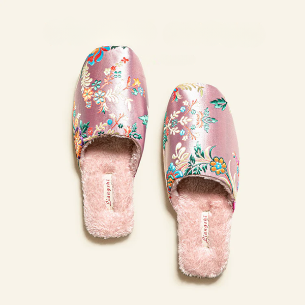 Pair of pink floral slippers with fluffy interior on a white background