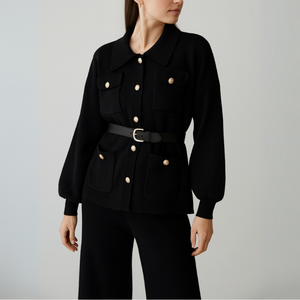 Woman wearing a black jacket with gold buttons on a gray background