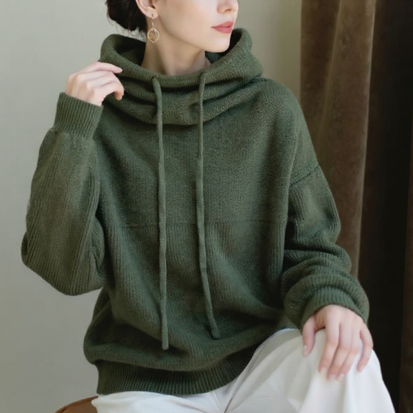 Person wearing a green hoodie sitting against a neutral background