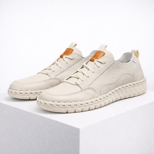 Pair of white sneakers with brown accents on a light gray background