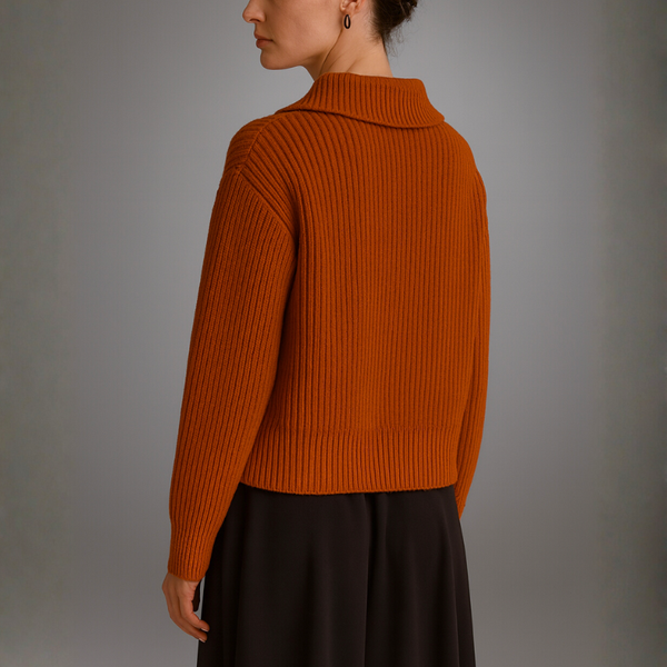 Person wearing an orange sweater against a gray background