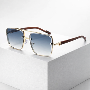 Sunglasses with gold frame and brown arms on a light gray surface