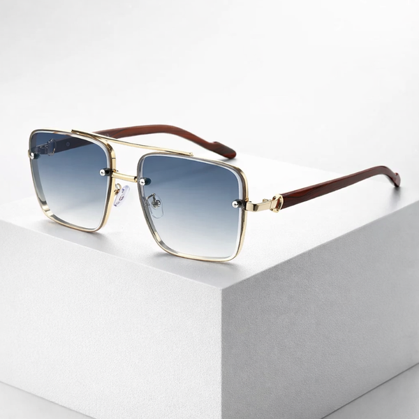 Sunglasses with gold frame and brown arms on a light gray surface