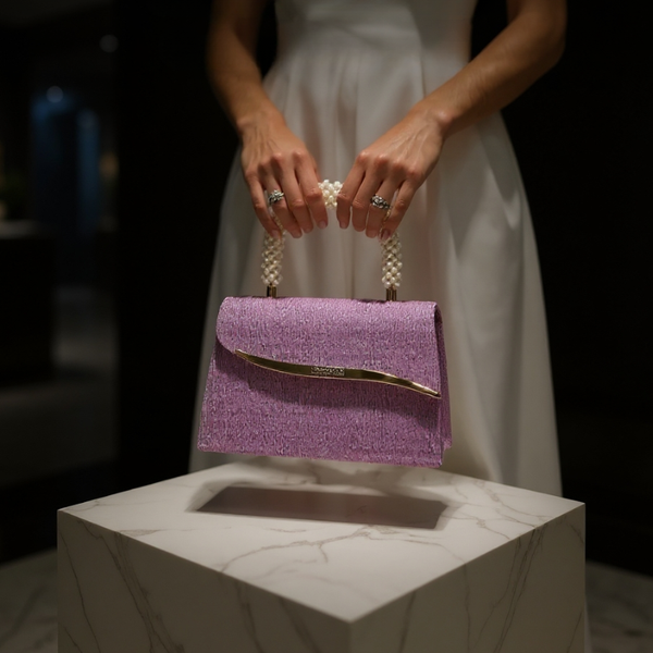 Purple glittery handbag with pearl handle held by a person in a white dress.