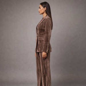 Woman wearing a brown velvet suit against a gray background