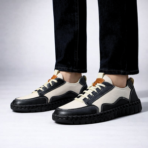 Black and white sneakers worn with dark jeans on a light gray background