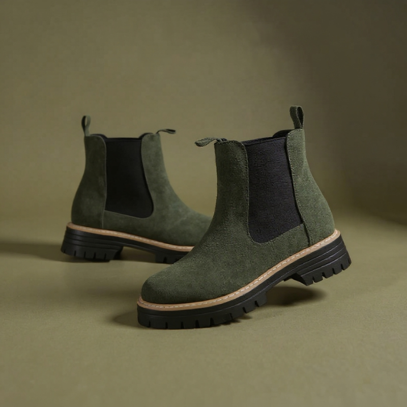 Pair of gray Chelsea boots on a beige fabric background
