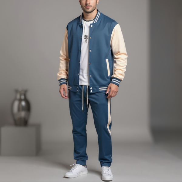 Man wearing a blue and beige varsity jacket with matching pants on a gray background