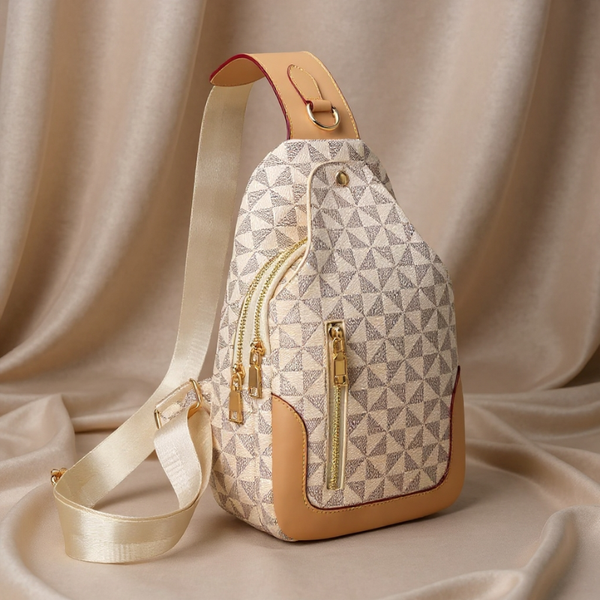 Patterned sling bag with gold zippers on a beige fabric background