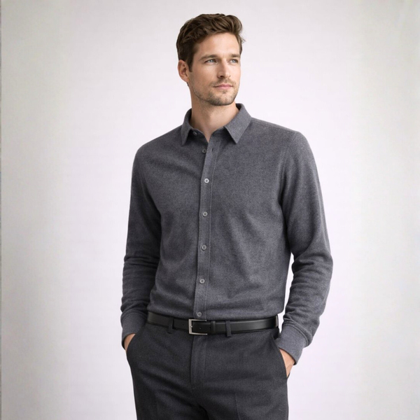 Man wearing a gray long-sleeve shirt and dark pants against a white background