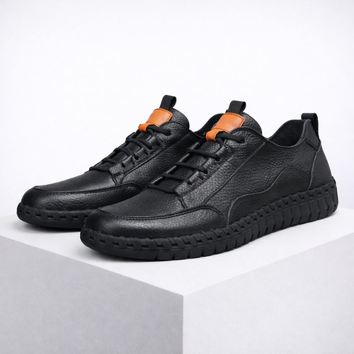 Pair of black leather shoes with orange accents on a white background