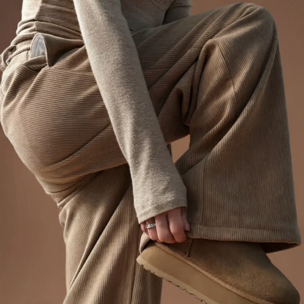 Person wearing brown corduroy pants and a matching jacket against a brown background