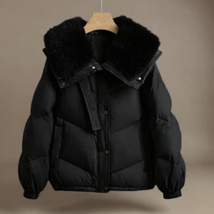 Black puffer jacket with fur collar on a wooden hanger against a brown background