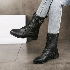Black leather boots worn with light gray jeans on a neutral background