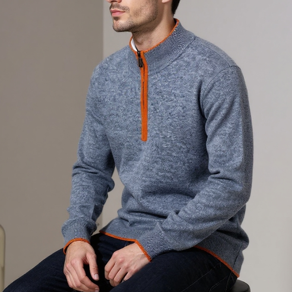 Man wearing a blue sweater with orange zipper sitting on a chair.
